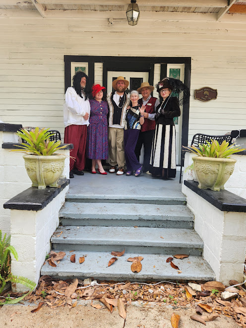 Group of people in vintage clothing standing on steps of old house
